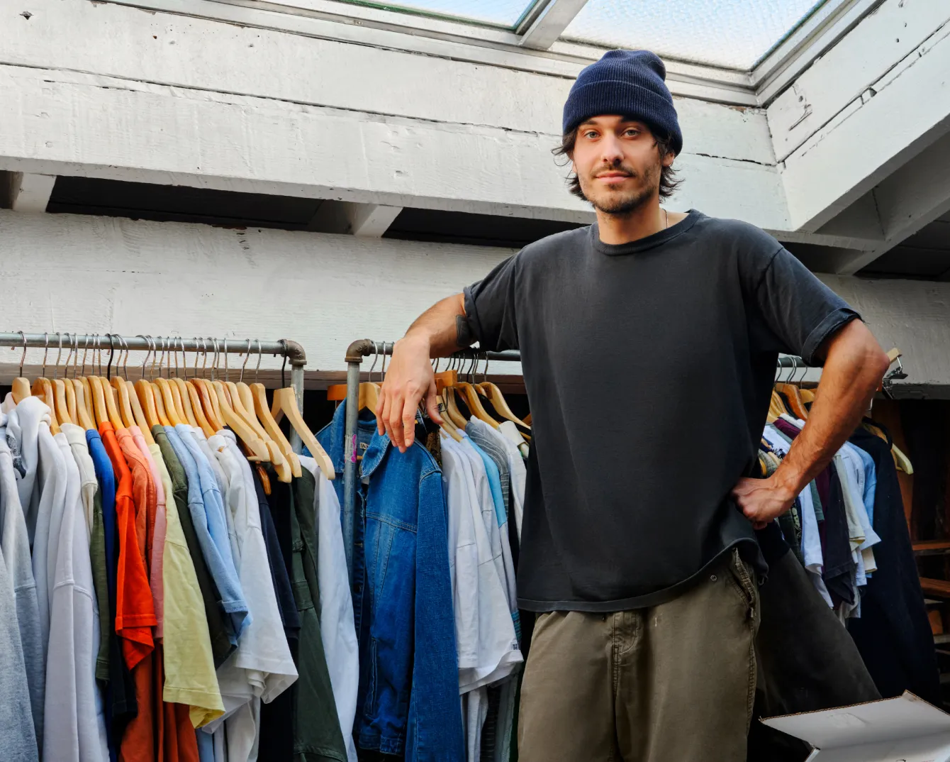 Man standing against a rack of clothes 